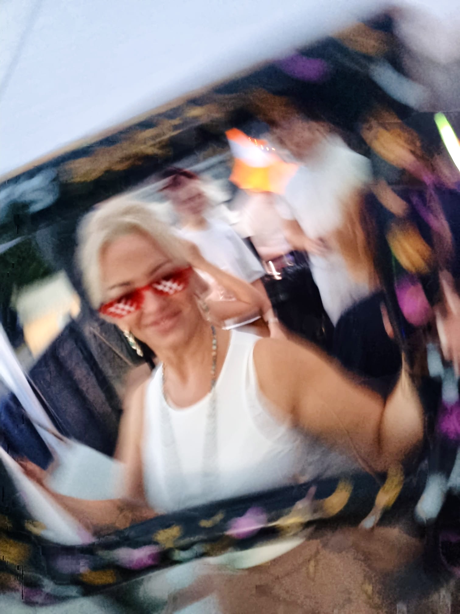 A smiling guest in heart-shaped sunglasses celebrating on the dancefloor at a DFRACTD event